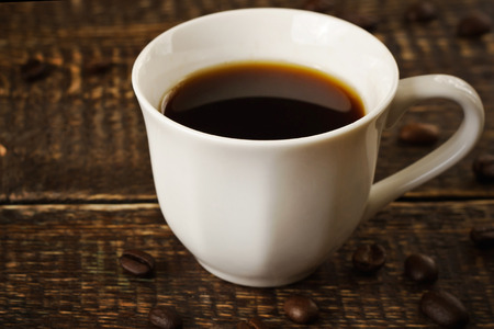 White porcelain cup with a dark coffee on the wooden tableの写真素材