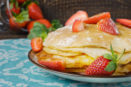Hot pancakes with strawberries and honey on the ceramic plate horizontalの写真素材