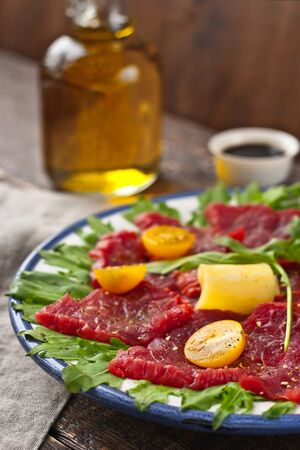 Carpaccio with arugula, tomatoes and cheese on the rustic tableの写真素材