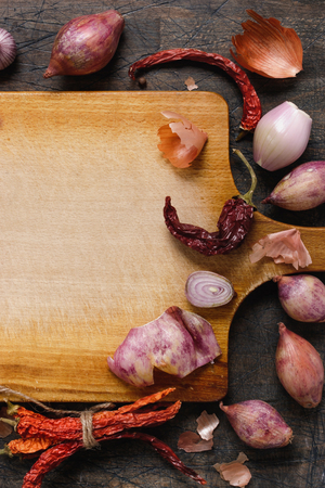 Wooden board with onions, garlic and pepper background verticalの写真素材