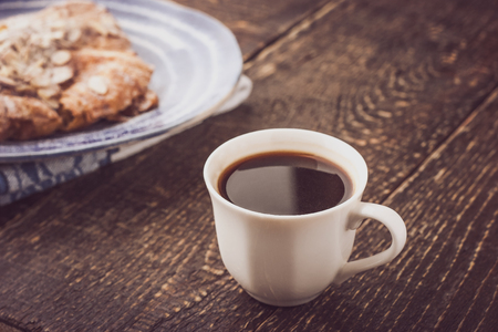 Cup of coffee with blurred croissant   on the blue ceramic plate horizontalの写真素材