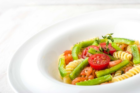 Pasta with vegetables and shrimps on the white plate horizontalの写真素材