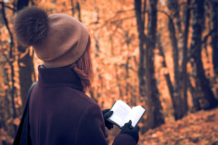Women with book in the autumn forestの写真素材