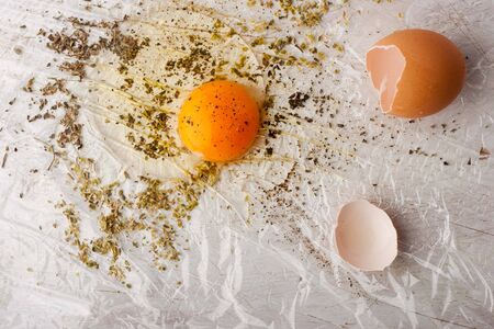 Broken egg with herbs mix on the white table