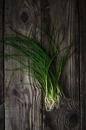 Stalks of green onions on a wooden table verticalの写真素材