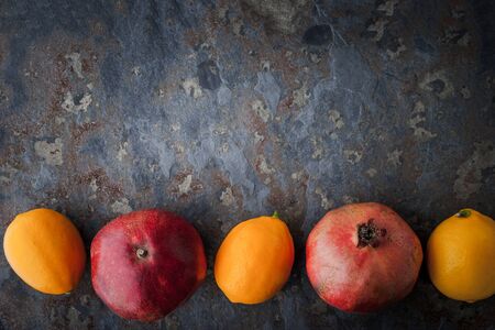 Lemons, pomegranates on the stone table horizontalの写真素材