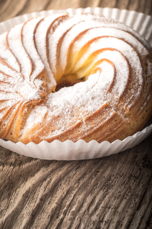 Cake in powdered sugar on a wooden table vertical