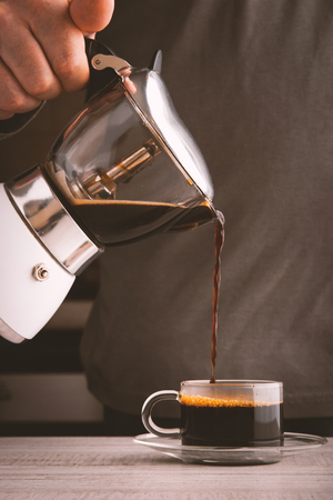 Man pouring coffee into a glass cup verticalの写真素材