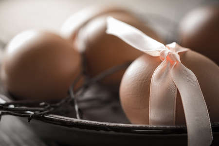 Eggs with  ribbon and branches on the old plate close-upの写真素材