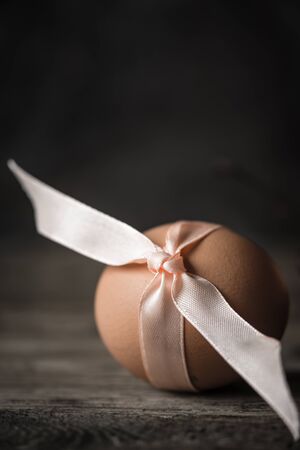 Egg with  ribbon on the wooden tableの写真素材