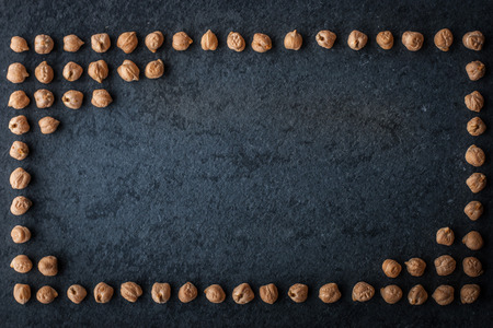 Frame of chick-peas on the dark stone backgroundの写真素材