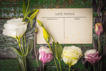 Eustoma flowers with postcard on the shabby wooden table top view