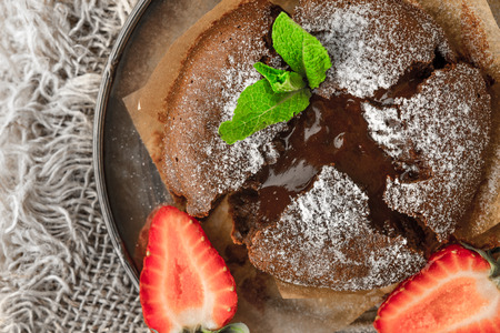 Chocolate fondant  with strawberry and mint on the metal plate top viewの写真素材