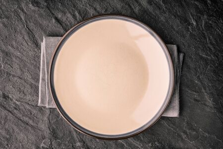 Ceramic plate on the dark stone table top view