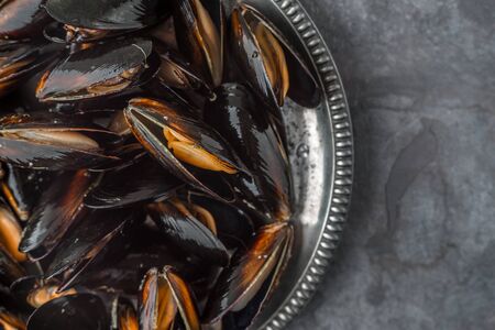 Open sash mussels on an old metal plate on a slate horizontalの写真素材