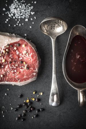 Marble ribeye steak, juniper, spoon, gravy boat, and salt into a blue-black slate verticalの写真素材