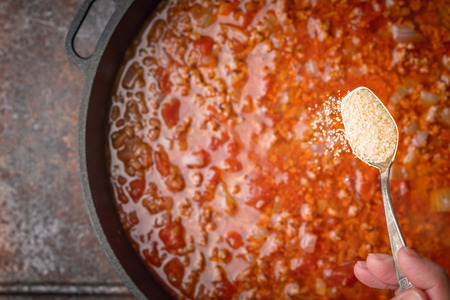 Spoon with sugar on the blurred pan with stew meat and tomatoesの写真素材