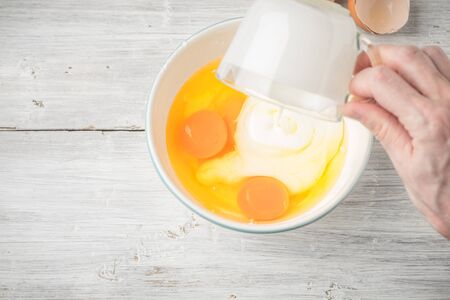 Mixing eggs and yogurt in the ceramic bowl