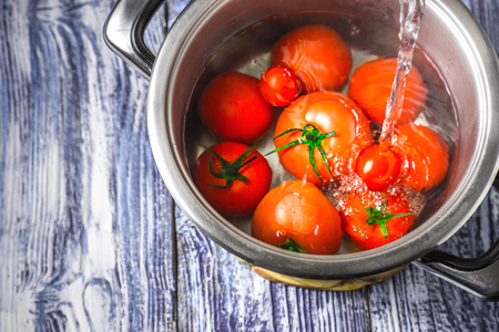 Stream of water, the tomatoes in a pot on a blue and white boards horizontalの写真素材