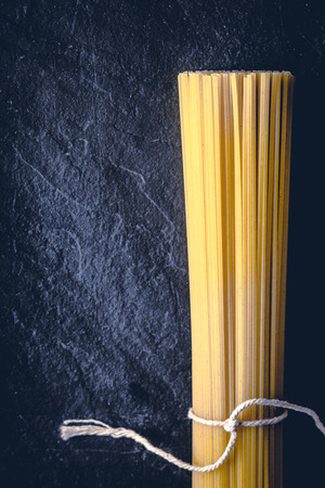 Raw spaghetti on the black stone background  verticalの写真素材