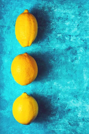 Yellow lemons on the cyan background verticalの写真素材