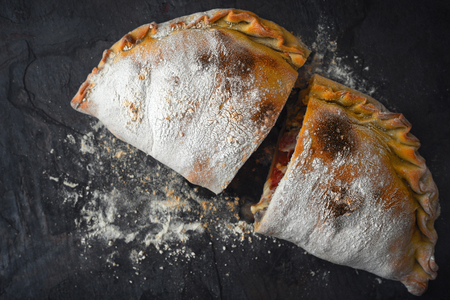 Sliced calzone with flour on the dark stone background top viewの写真素材