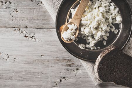 Fresh cottage cheese on the  metal plate  with bread on the white wooden table horizontalの写真素材