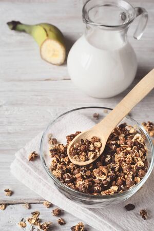 Granola in a glass bowl on a white wooden tableの写真素材