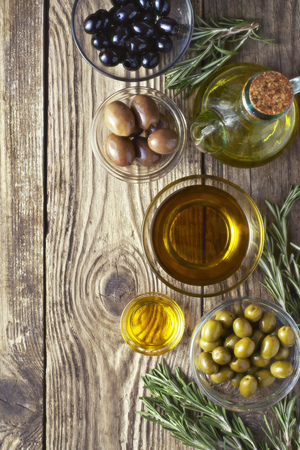 Olives with olive oil and rosemary on the wooden tableの写真素材