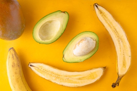 Bananas and avocados on a yellow background horizontalの写真素材