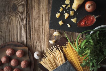 Ingredients for cooking spaghetti, meatballs with cheese and fresh herbs on the table horizontal copy spaceの写真素材