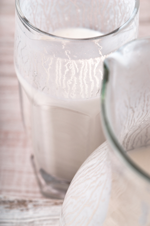 Glass of kefir and a jug on the wooden table verticalの写真素材