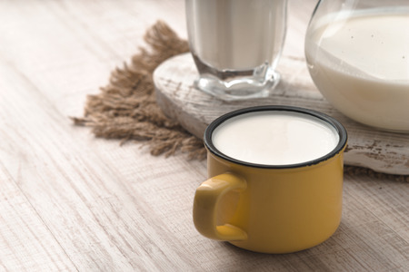 Glass, pitcher, cup of kefir and napkin on a white table horizontalの写真素材