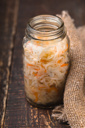 Sauerkraut in a glass jar and rustic napkin on wooden boards verticalの写真素材