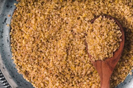 Placer grain bulgur on a tin plate and spoon close-up horizontalの写真素材