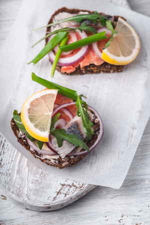 Sandwiches with salmon, herring, lemon on a white stand verticalの写真素材