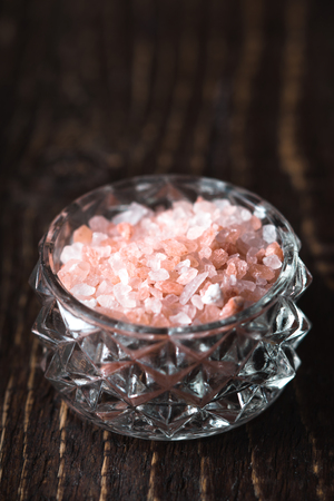 Pink salt in a glass bowl on a wooden table verticalの写真素材