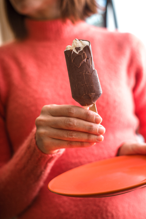 Woman eating chocolate covered popsicleの写真素材