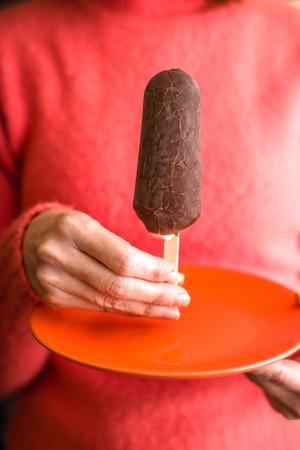 Chocolate covered popsicle in the woman` s handの写真素材