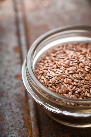Flax seeds in the glass bowl on the metal backgroundの写真素材