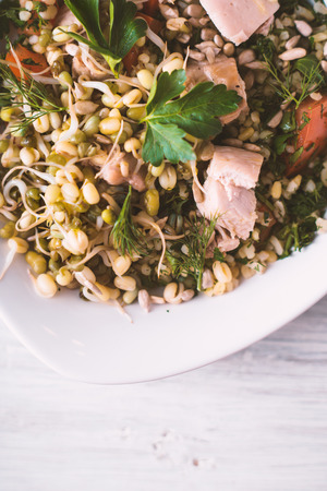 Salad with chicken and beans in a bowl on a white table verticalの写真素材