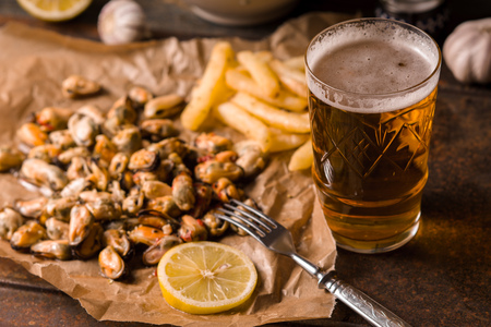 Mussels, fried potatoes on parchment and beer in a glass horizontalの写真素材