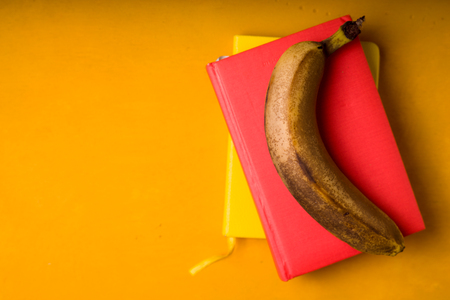One banana on notepads on a bright backgroundの写真素材