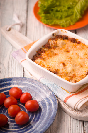 Homemade Meat lasagna and tomato, lettuce on wooden standの写真素材