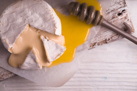 Brie cheese, slice, honey on parchment and on a stand diagonalの写真素材