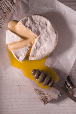 Brie cheese with honey on the white wooden tableの写真素材