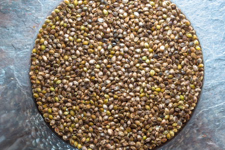 Glass bowl with cannabis seeds on a blue stone close-upの写真素材