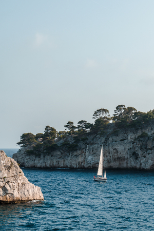 Sailboat on waves against the background of rocks