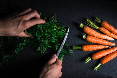 Cutting green carrot leaves and carrotsの写真素材