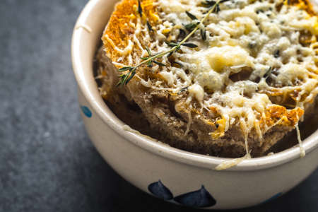 French onion soup in a ceramic bowl on a gray stoneの写真素材